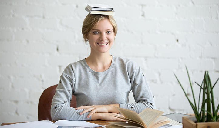 Woman sitting at desk with perfect posture and books balancing on her head.